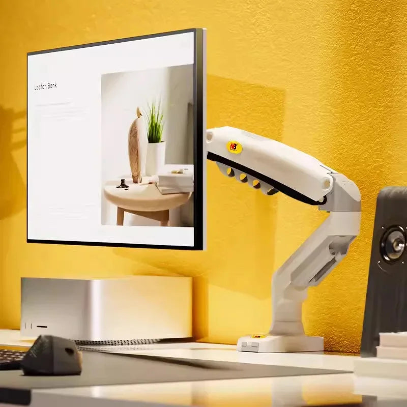 Ergonomic monitor arm holding a flat screen on a modern desk setup with yellow wall.