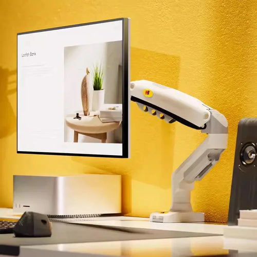 Ergonomic monitor arm holding a flat screen on a modern desk setup with yellow wall.