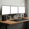 Person working at a desk with multiple monitors and gaming equipment.