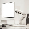 Ergonomic monitor arm holding a flat screen on a modern desk setup with yellow wall.