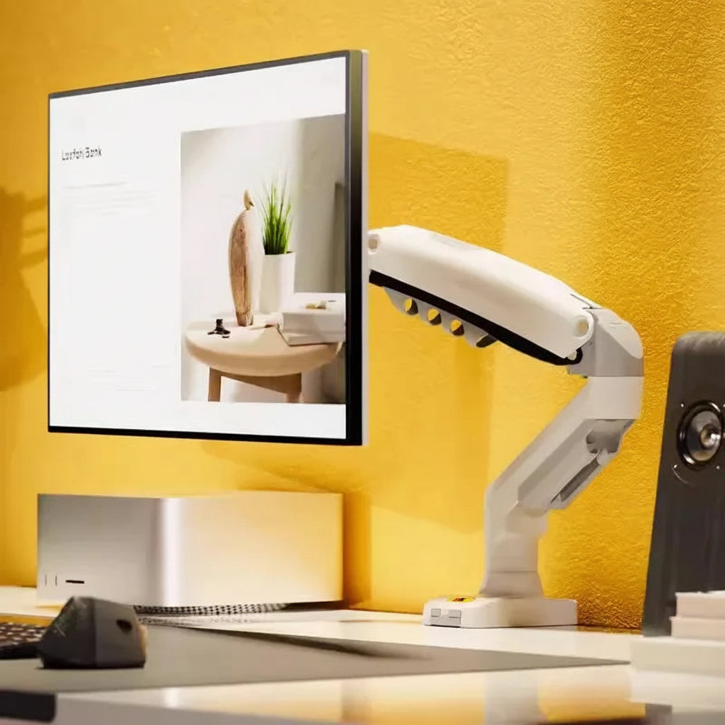 Ergonomic monitor arm holding a flat screen on a modern desk setup with yellow wall.